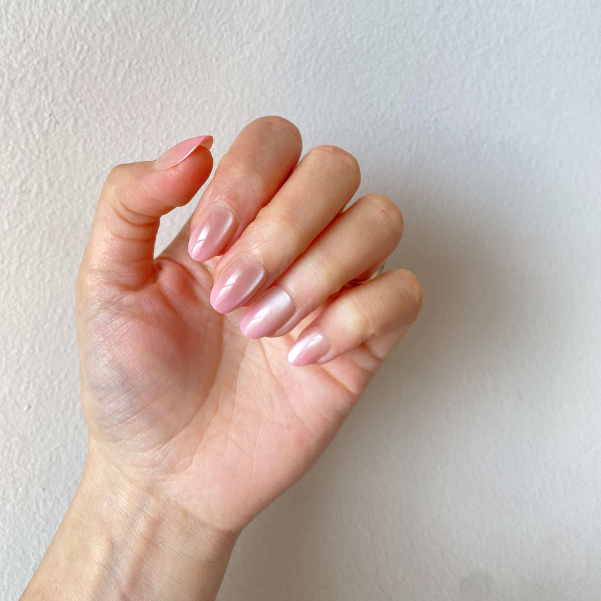 Pearl blush chrome press-on nails curled fist pose