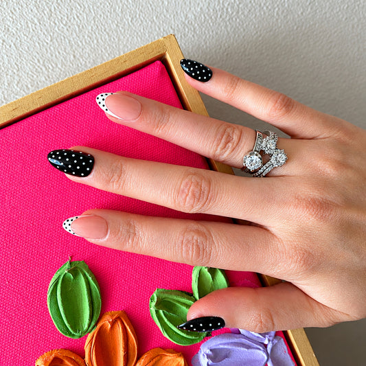 Black polka dot press-on nails styled with pink prop box