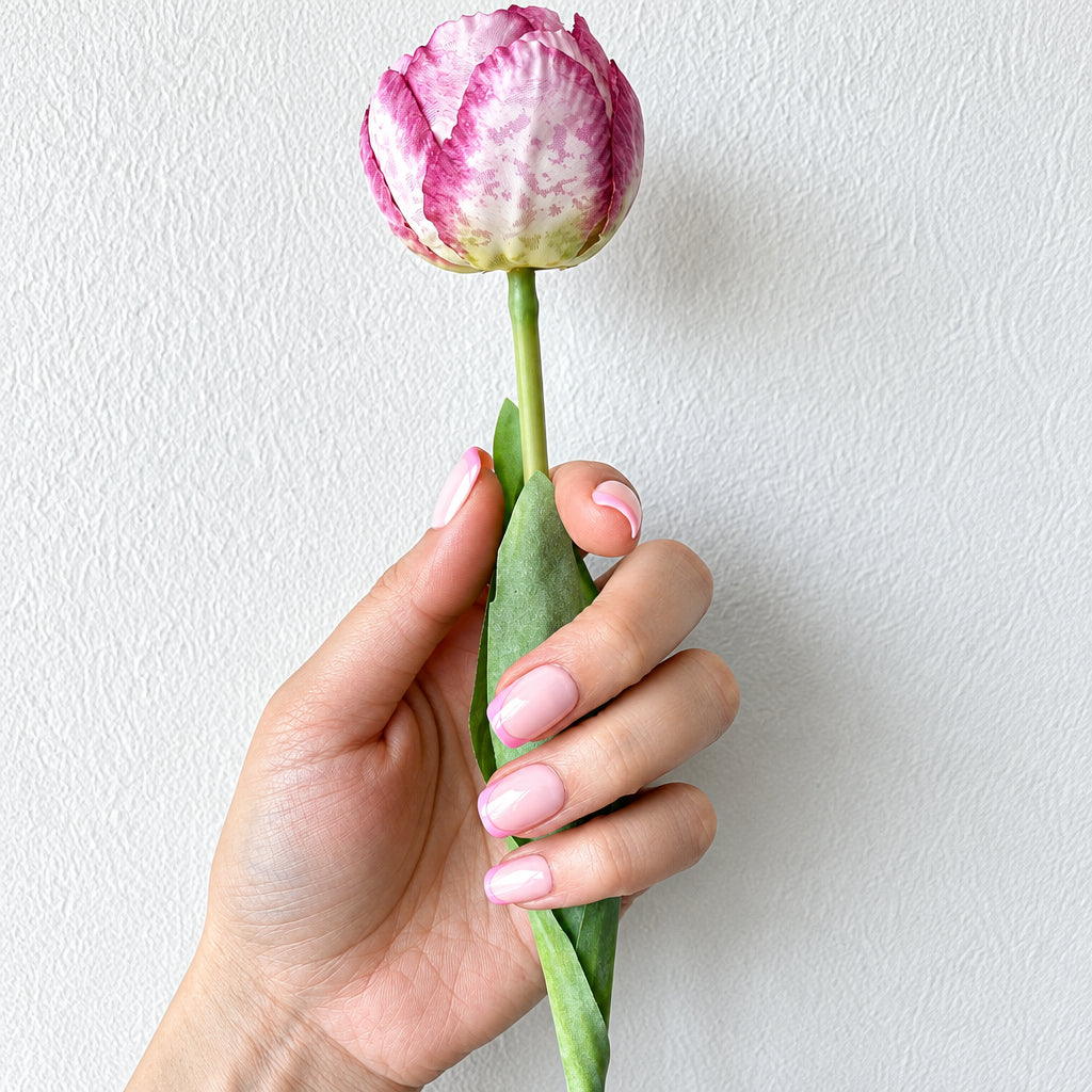 Baby pink glazed press-on nails fist against linen background